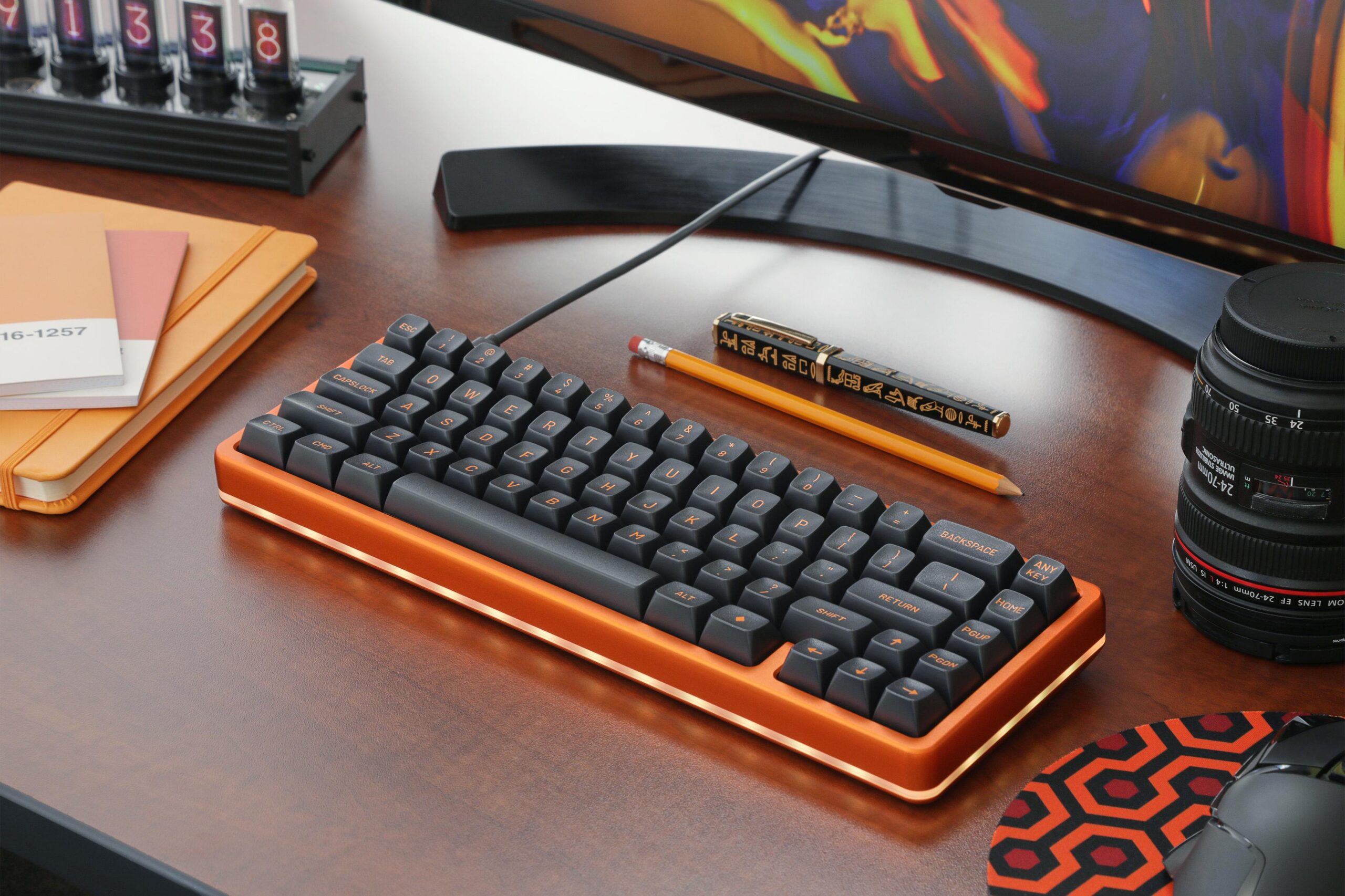 Orange case keyboard with black keycaps with orange lettering sitting in a nice and organized desk